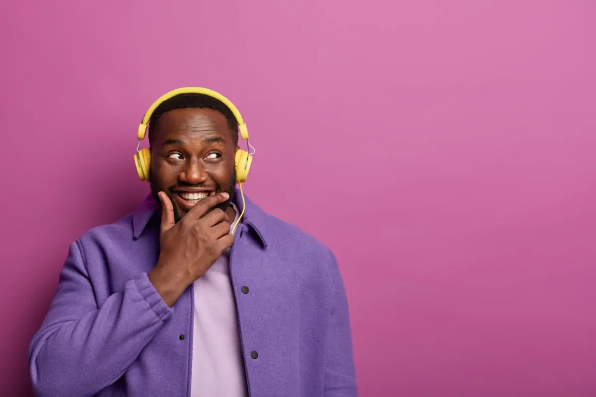 A man in yellow headphones listening, mid-smile